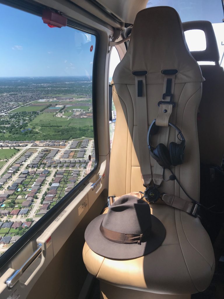 Rear-facing helicopter seat from inside of cabin during flight with hat on it.