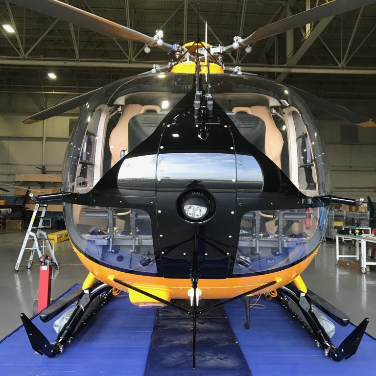 Yellow H145 Airbus Helicopter from the front on a blue mat in a hangar.